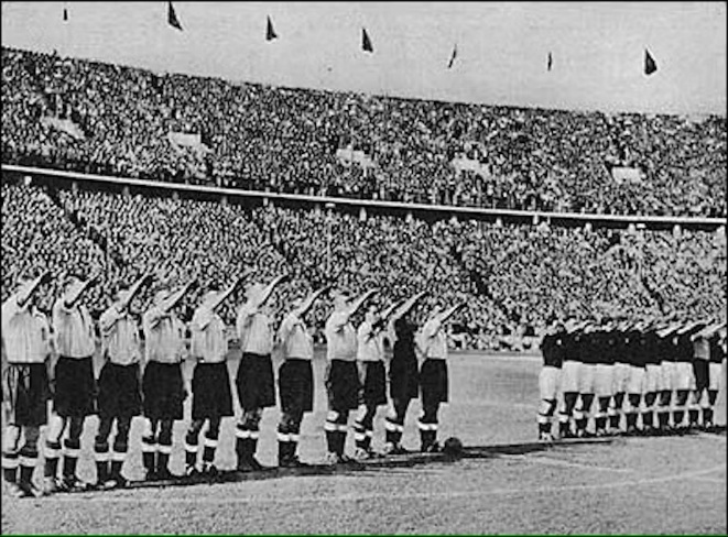 A group of people saluting in a stadium Description automatically generated